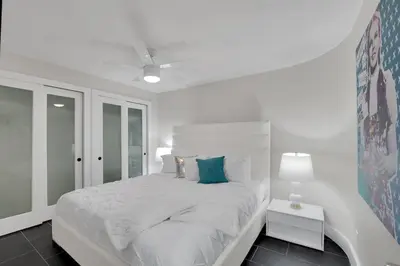 a white bedroom with a large bed with blue pillows at Iconic! Miami Skyline & Water Views in Miami