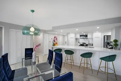a kitchen with a glass table and blue chairs at Unforgettable! Water & Park Views, 4 Bedrooms! in Miami