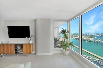 a living room with a tv and a large window at Champagne & Ice! Water Views, 2 Private Balconies! in Miami