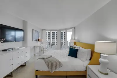 a white bedroom with a bed and a tv at Hello Gorgeous! Water & City Skyline Views! in Miami