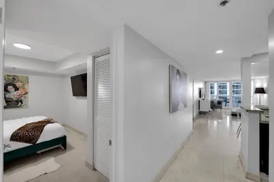 a white bedroom with a bed and a kitchen at Hello Gorgeous! Water & City Skyline Views! in Miami