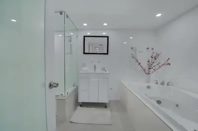a white bathroom with a large tub and a sink at Velvet Sky! Water & Park Views! in Miami