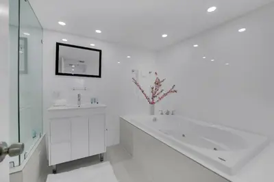 a white bathroom with a sink and a mirror at Velvet Sky! Water & Park Views! in Miami
