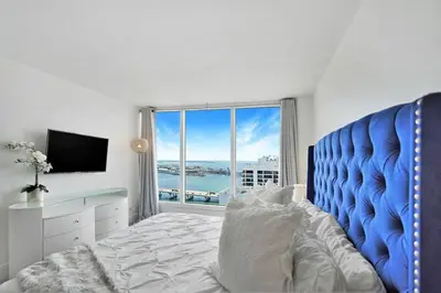 a bedroom with a blue bed and a large window at Spectacular! Penthouse with Direct Water Views! in Miami