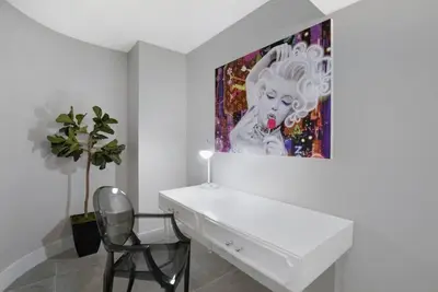 a white desk with a chair and a painting on the wall at Blue Moon! In the lap of luxury and brand new! in Miami