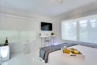a white bedroom with a bed with a tray of fruit on it at Bars B&B South Beach Hotel in Miami Beach