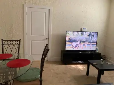 a living room with a flat screen tv and a table at Pretty Private Room, near the Airport - Free parking - 02 in Miami