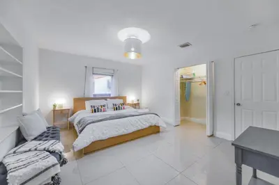 a white bedroom with a bed and a table at Discover Serenity in this Tranquil Miami Home in Miami