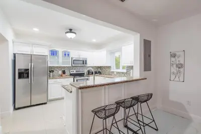 a kitchen with a refrigerator and two bar stools at Discover Serenity in this Tranquil Miami Home in Miami