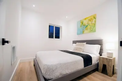 a white bedroom with a bed and two windows at Casa Canal in North Miami Beach