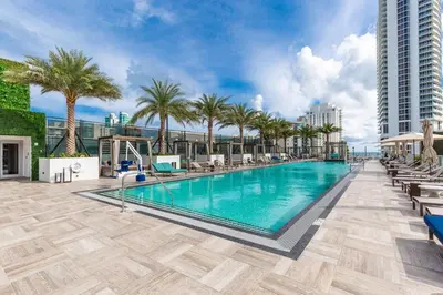 a swimming pool with palm trees and a building at 23rd-Floor Views • Pool Gym Beach Service in Hollywood