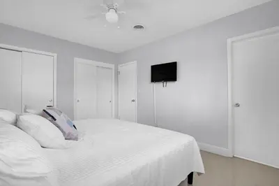 a white bedroom with a bed and a flat screen tv at Outdoor Paradise in Fort Lauderdale