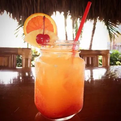 a mason jar of orange juice with a cherry and a straw at Caribbean Resort by the Ocean in Hollywood