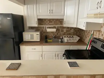 a kitchen with white cabinets and a black refrigerator at Cozy rooms in cute house, close to Miami airport - Free parking in Miami