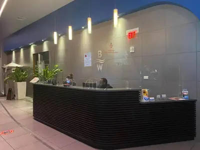 a lobby with a counter with a person sitting at it at Relaxing BeachWalk Getaway, Studio for 4 Guests in Hallandale Beach