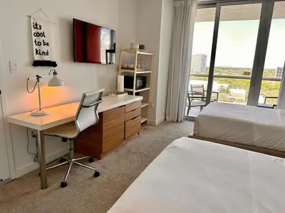 a bedroom with a desk and a bed and a bed and a desk and chair at 2 Full Beds Ocean Air, Relaxing Studio Stay in Hallandale Beach