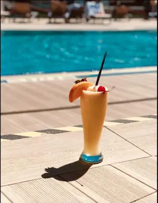 a drink sitting on a table next to a pool at Studio with 2 Full Beds, Perfect Beach Location in Hallandale Beach