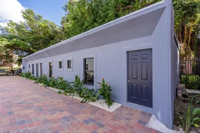 a white building with a black door on a sidewalk at Spectacular Apartment near Brickell in Miami