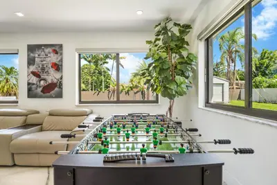 a living room with a foosball table in the middle at The Palms -Mini Golf , Foosball Table, Heated Pool ,Baby items ,BBQ in Miami