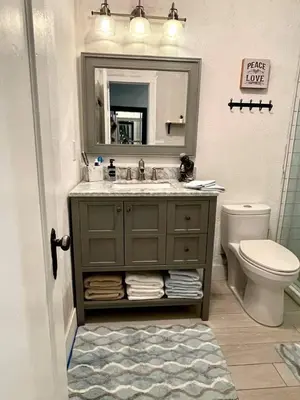 a bathroom with a sink and a toilet and a mirror at Orange You Glad you came in Miami
