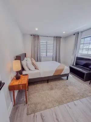 a bedroom with a bed and a table with a lamp at Zoka House 5 mints from Brickell in Miami
