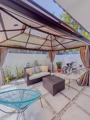 a patio with a couch and chairs under a large umbrella at Zoka House 5 mints from Brickell in Miami