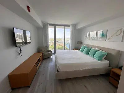 a bedroom with a large bed with green pillows at Miami Beach, Full Kitchen & Style -A in Hallandale Beach