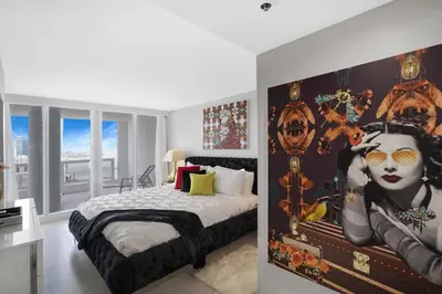 a bedroom with a bed and a large painting on the wall at Higher Love! Water Views and Cool Vibes in Miami