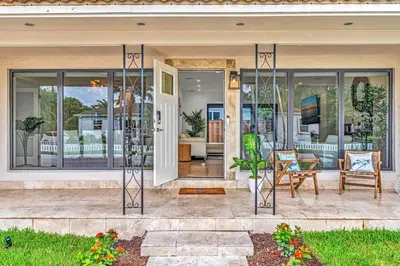 a home with glass doors and a patio at Tropical Oasis With heated pool 10 mins airport & 5 mins Beach in Hollywood