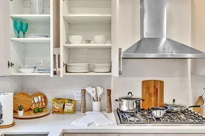 a kitchen with white cabinets and a stove with dishes at Tropical Oasis With heated pool 10 mins airport & 5 mins Beach in Hollywood