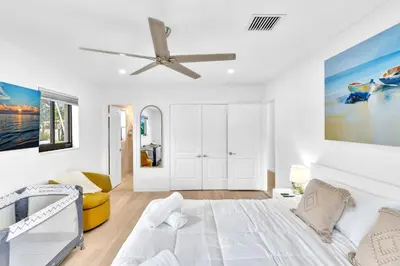 a white bedroom with a bed and a ceiling fan at Tropical Oasis With heated pool 10 mins airport & 5 mins Beach in Hollywood