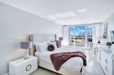a white bedroom with a large bed and a table at Stay in Love! Miami Skyline Views, Renovated in Miami