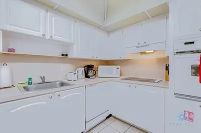 a white kitchen with white cabinets and appliances at Paradise Retreat, Near Beach, Casino, and More in Hollywood