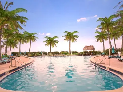 a swimming pool with palm trees in a resort at Paradise Retreat, Near Beach, Casino, and More in Hollywood