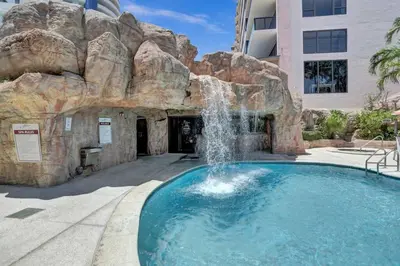 a swimming pool with a waterfall in front of a building at Cozy 2 Bedroom Ocean View Beach Service 707 in Miami Beach