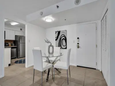 a dining room with a glass table and white chairs at Cozy 2 Bedroom Ocean View Beach Service 707 in Miami Beach
