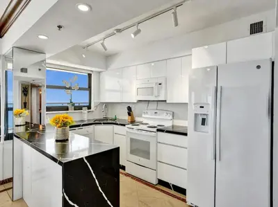 a kitchen with white cabinets and a white refrigerator at Huge Terrace Oceanfront Condo Beach Service 1502 in Miami Beach