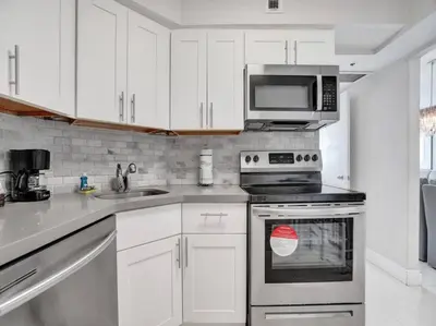 a kitchen with white cabinets and a stove and a microwave at Fantastic condo w beach service 615 in Miami Beach