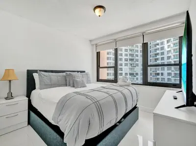 a white bedroom with a large bed and a window at Fantastic condo w beach service 615 in Miami Beach