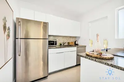 a stainless steel refrigerator in a kitchen with white cabinets at Free Parking - Bay View - Pool -Step To Beach in Hollywood