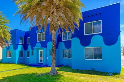 a blue building with a palm tree in front of it at Free Parking - Bay View - Pool -Step To Beach in Hollywood