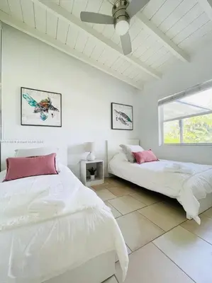 a white bedroom with two beds and a window at Tropical Oasis House Private Pool Family Yard in Fort Lauderdale