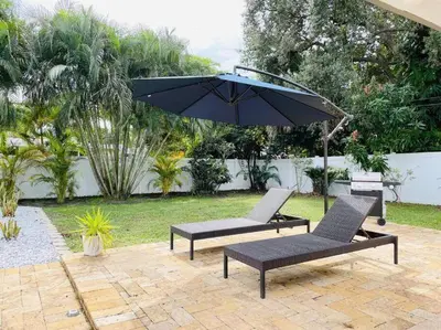 a patio with two chairs and an umbrella at Tropical Oasis House Private Pool Family Yard in Fort Lauderdale