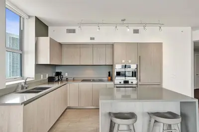 a kitchen with a large island with two bar stools at 2BR & 2BA Corner Suite Ocean Views at Hyde Beach House in Hollywood