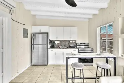 a kitchen with white cabinets and a table and stools at New Year and Holiday Charming Miami Riverfront Stay! in Miami