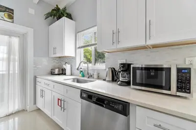 a white kitchen with a sink and a microwave at Seashell Walk To The Beach Comfy Beds Firepit Pool in Fort Lauderdale