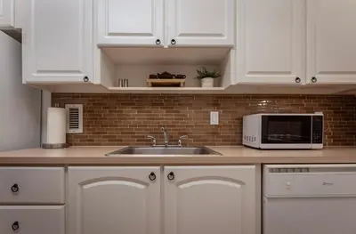 a kitchen with white cabinets and a sink and a microwave at Tides Condominiums in Hollywood