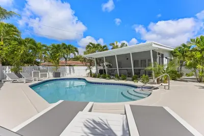 a swimming pool in front of a house at Coconut Walk To The BeachComfy Beds Firepit Pool in Fort Lauderdale