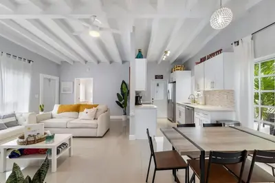 a white living room with a table and a kitchen at The Sandbar Walk To Beach Comfy Beds Firepit Pool in Fort Lauderdale