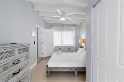 a white bedroom with a bed and a ceiling fan at The Sandbar Walk To Beach Comfy Beds Firepit Pool in Fort Lauderdale